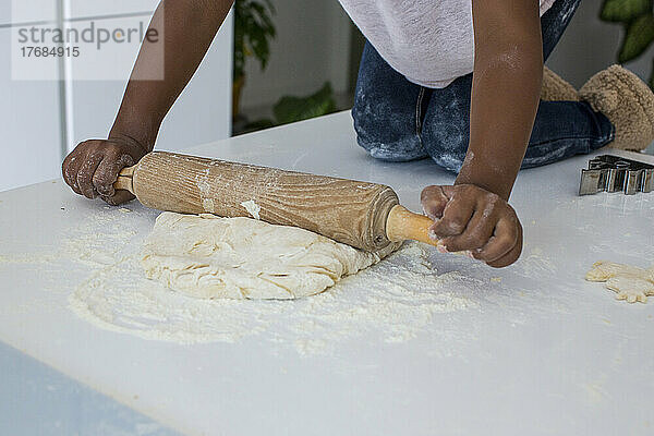Girl rolling dough in kitchen