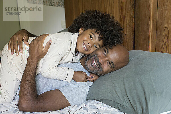 Lächelnder Vater und Tochter entspannen sich im Bett