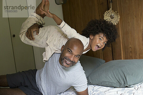 Lächelnder Vater trägt seine Tochter im Schlafzimmer auf der Schulter