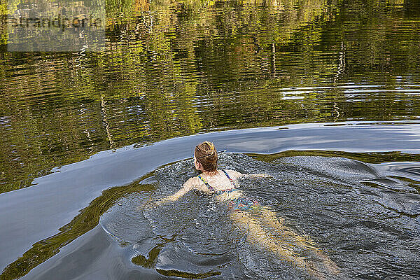 Unbeschwerte Frau beim Schwimmen in einem ruhigen Sommerfluss