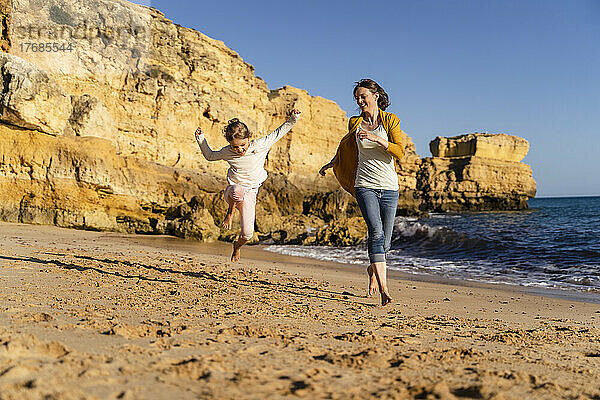 Glückliche Mutter mit Tochter  die am Strand läuft