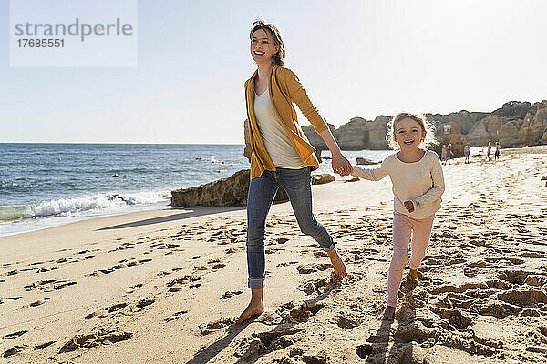 Glückliche Mutter mit Tochter  die am Strand spazieren geht