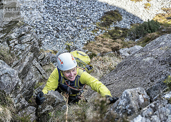 Active senior woman climbing rocky mountain