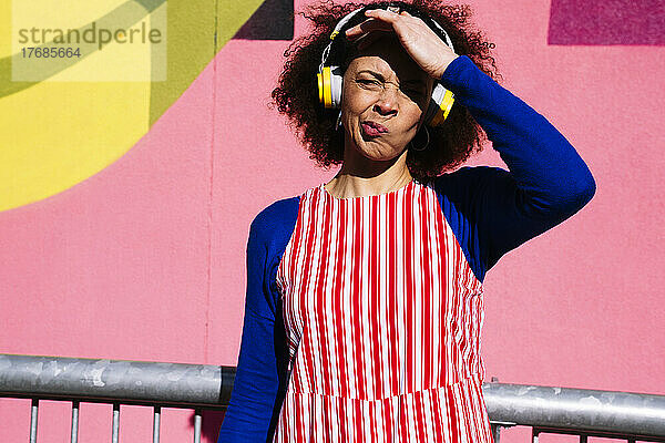 Frau mit Kopfhörern schirmt die Augen ab  um sie vor Sonnenlicht zu schützen