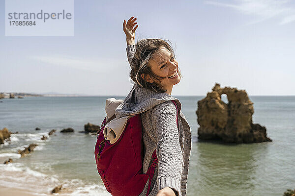 Glückliche Frau  die an einem sonnigen Tag den Urlaub vor dem Meer genießt