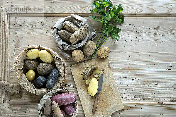 Parsley and different varieties of raw potatoes on rustic wooden background