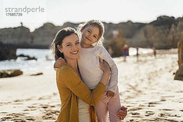Glückliche Mutter mit Tochter am Strand an einem sonnigen Tag