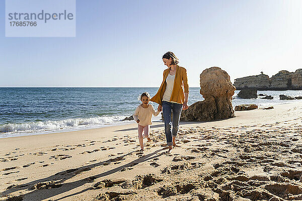 Mutter und Tochter gehen am Strand entlang