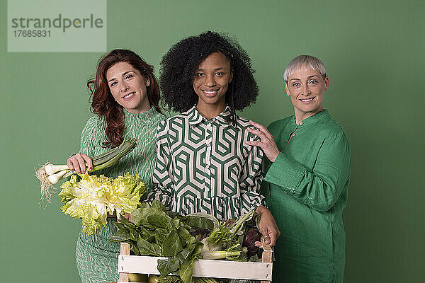 Lächelnde Freunde mit Gemüse vor grünem Hintergrund