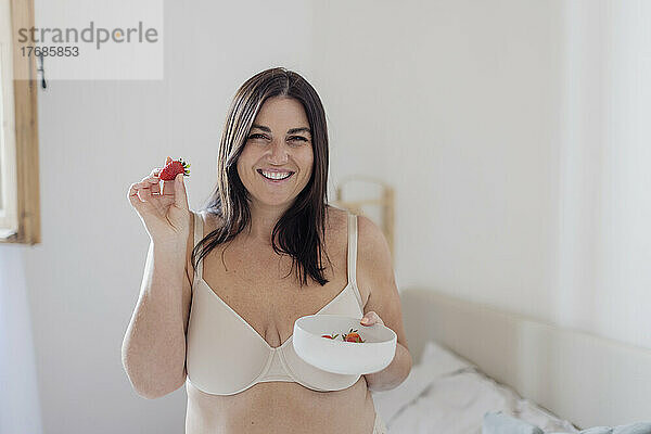 Glückliche Frau hält Erdbeere zu Hause