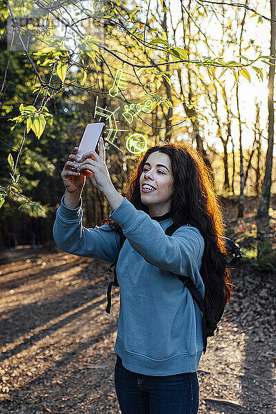 Frau benutzt Smartphone mit erweiterten Symbolen im Wald