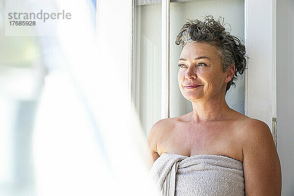 Smiling mature woman with short hair wearing towel at home