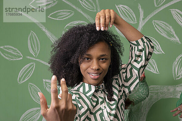Frau mit Afro-Frisur gestikuliert vor grüner Wand