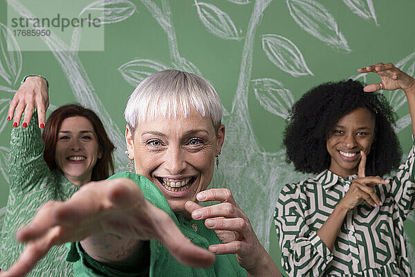 Glückliche reife Frau  die mit Freunden vor einer grünen Wand steht