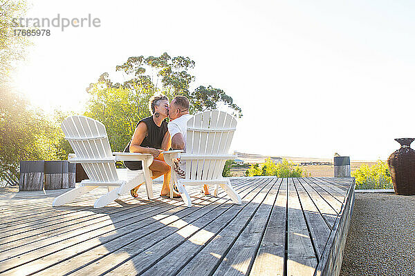 Ein Paar küsst sich und sitzt auf einem Stuhl auf der Terrasse