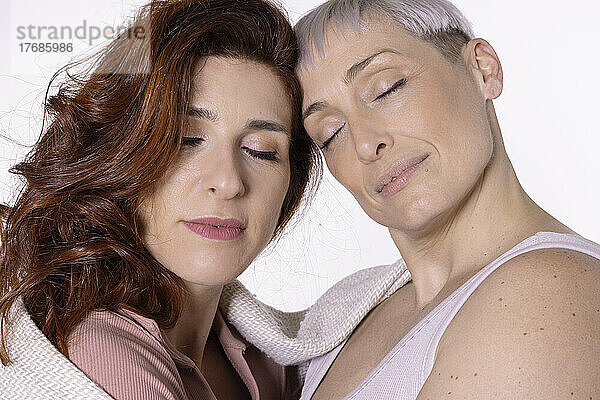Friends with eyes closed against white background