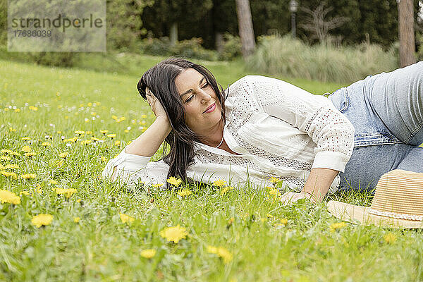 Lächelnde Frau liegt auf Gras im Park