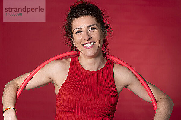 Glückliche Frau mit Plastikreifen vor rotem Hintergrund