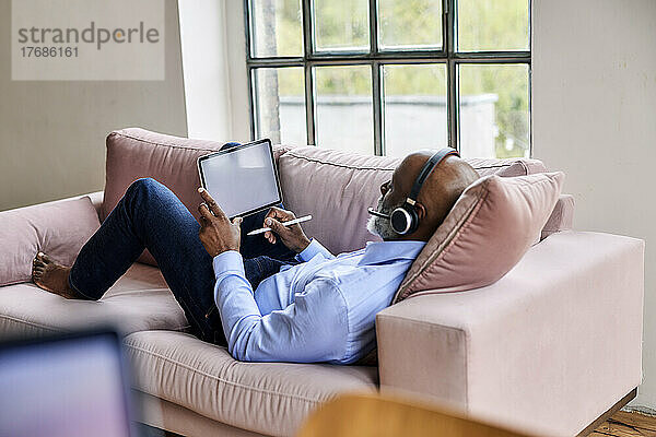 Geschäftsmann mit Headset und Tablet-PC auf dem heimischen Sofa