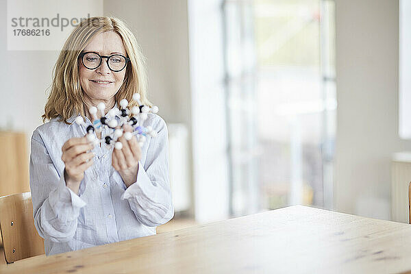 Lächelnde Frau untersucht molekulare Struktur am Tisch