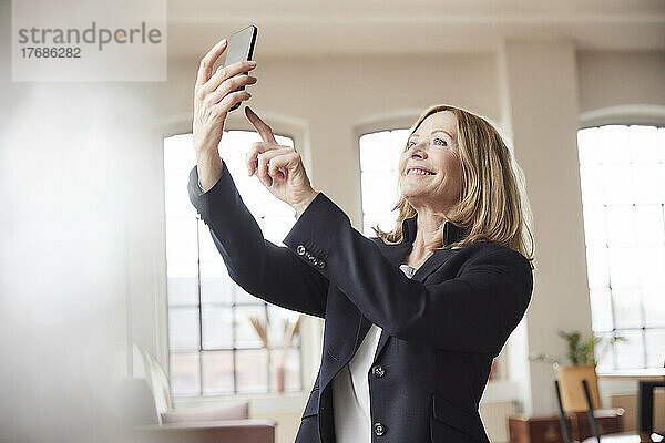 Glückliche Geschäftsfrau  die zu Hause ein Selfie mit dem Smartphone macht