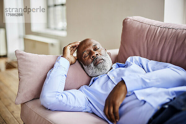 Geschäftsmann mit Glatze schläft zu Hause auf dem Sofa