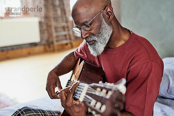 Mann mit Brille spielt zu Hause Gitarre