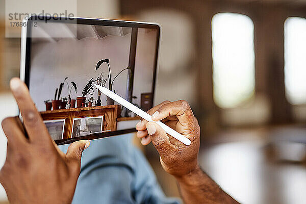 Reifer Mann benutzt Tablet-PC mit digitalisiertem Stift zu Hause