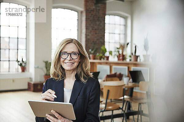 Lächelnde Geschäftsfrau mit Tablet-PC  die zu Hause im Wohnzimmer arbeitet