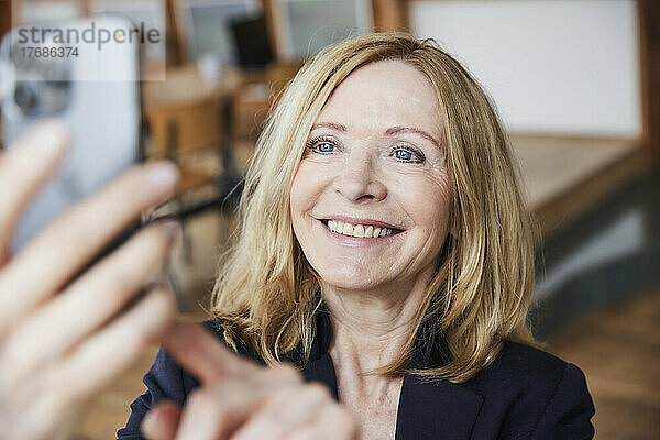 Lächelnde Frau  die zu Hause ein Selfie mit dem Smartphone macht