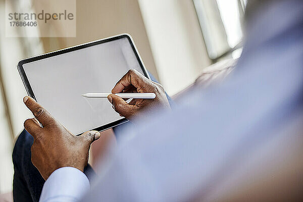 Geschäftsmann  der zu Hause einen digitalisierten Stift auf einem Tablet-Computer verwendet