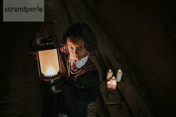 Mädchen mit Laterne im Hexenkostüm steht in einem gruseligen dunklen Tunnel