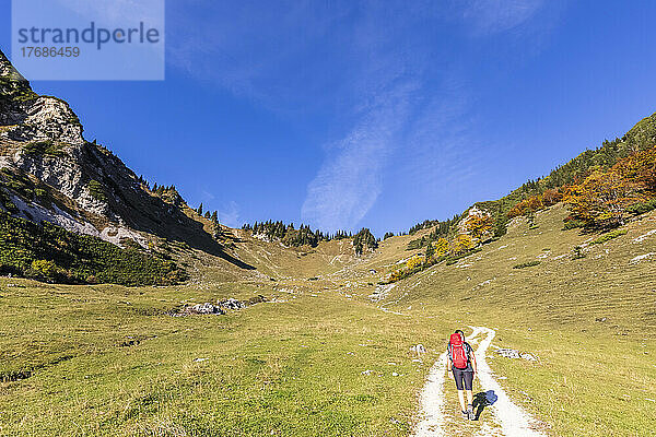 Germany  Bavaria  Female hiker following road to Geigelstein mountain