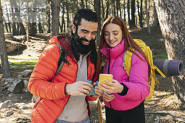 Glückliches Paar teilt Smartphone im Wald