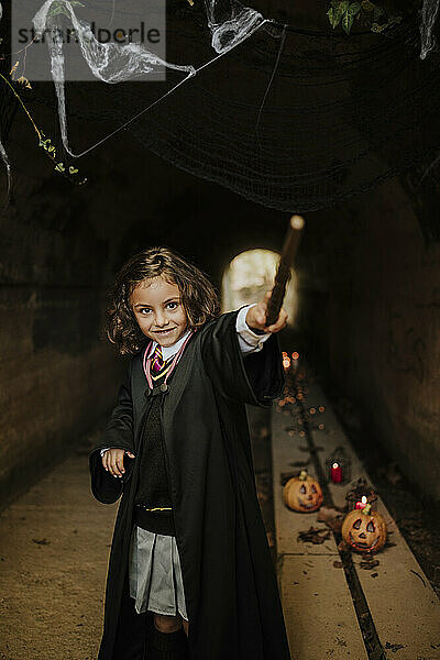 Lächelndes Mädchen im Hexenkostüm  das an Halloween Spaß im Tunnel hat