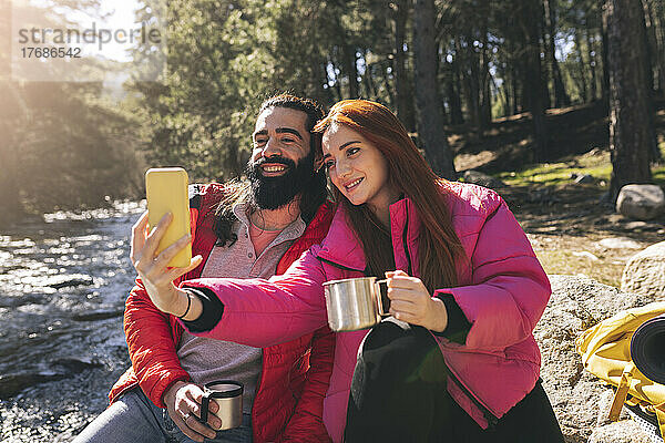 Junge Frau macht an einem sonnigen Tag ein Selfie mit einem bärtigen Mann per Smartphone