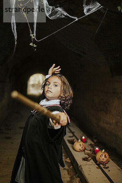 Mädchen im Hexenkostüm amüsiert sich zu Halloween im gruseligen Tunnel