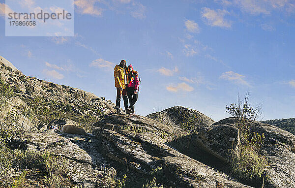 Paar steht an einem sonnigen Tag zusammen auf einem Felsen