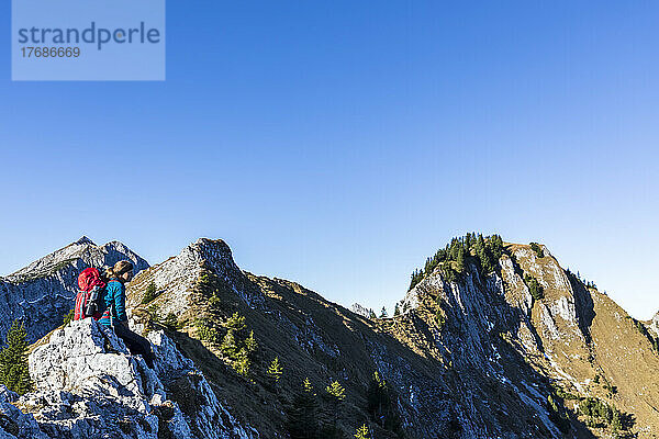 Deutschland  Bayern  Wanderin entspannt auf einem Berggipfel in den Ammergauer Alpen