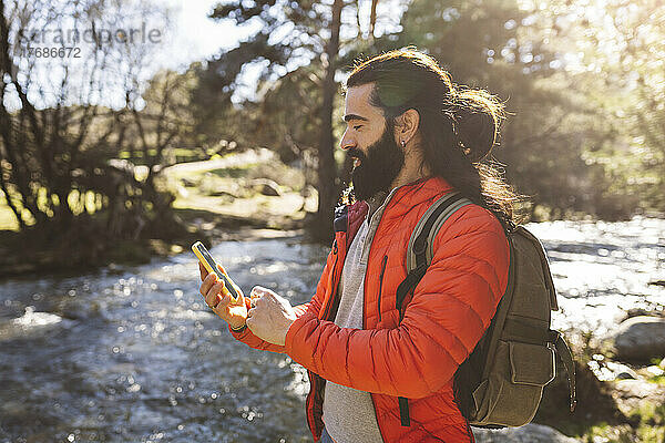 Bärtiger Mann benutzt Smartphone im Wald