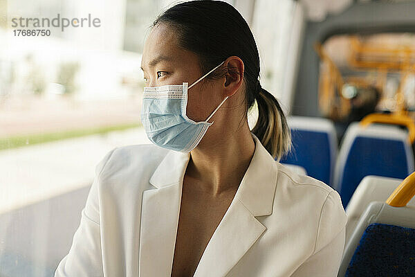 Geschäftsfrau mit Schutzmaske pendelt in der Straßenbahn