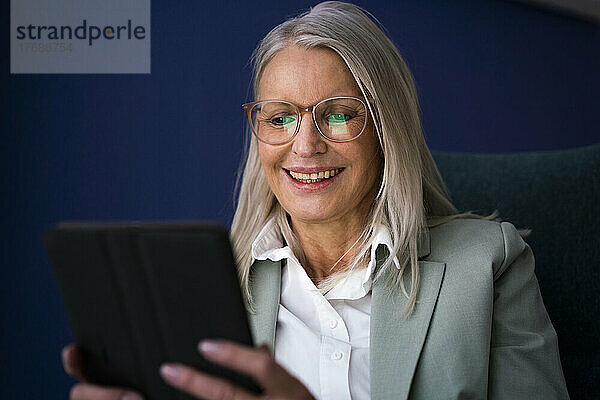 Lächelnde ältere Geschäftsfrau  die einen Tablet-PC verwendet