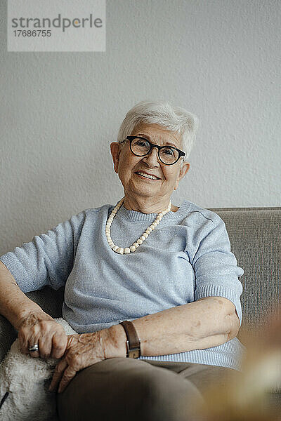 Glückliche ältere Frau  die zu Hause auf dem Sofa sitzt