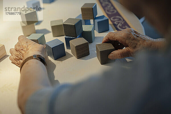Senior woman playing with toy blocks at home