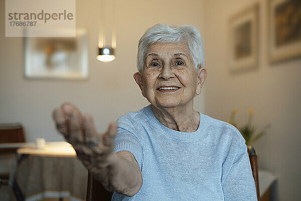 Lächelnde ältere Frau  die zu Hause die Hand gibt