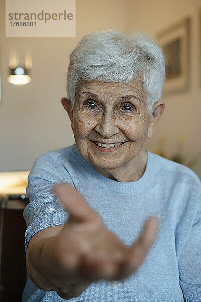 Glückliche ältere Frau  die zu Hause die Hand gibt