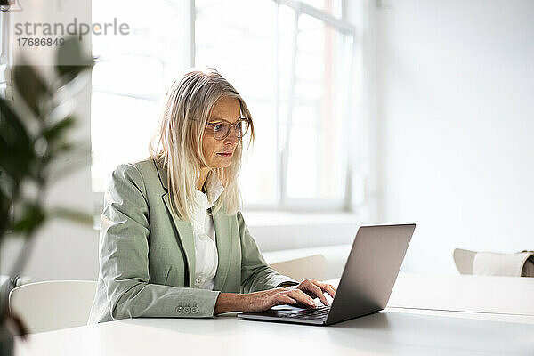 Ältere Geschäftsfrau arbeitet am Laptop am Schreibtisch im Büro