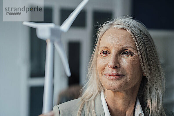Geschäftsfrau betrachtet Windturbinenmodell im Büro