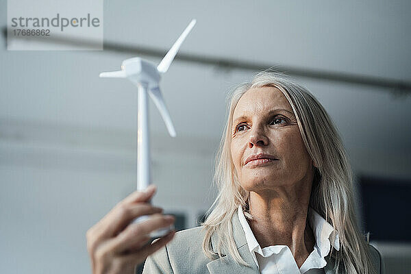 Geschäftsfrau hält Windturbinenmodell im Büro