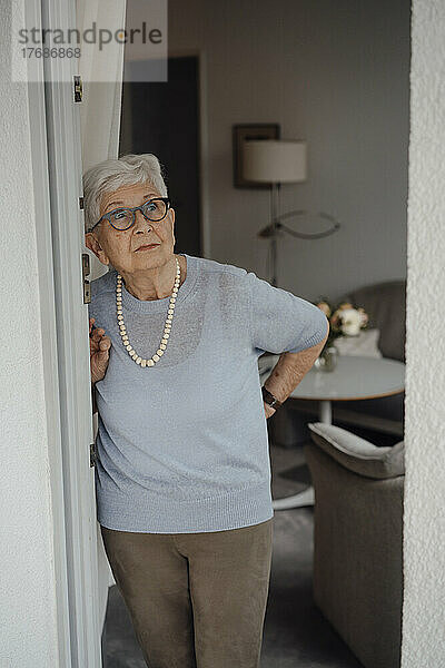 Ältere Frau mit weißen Haaren steht am Wohnungseingang